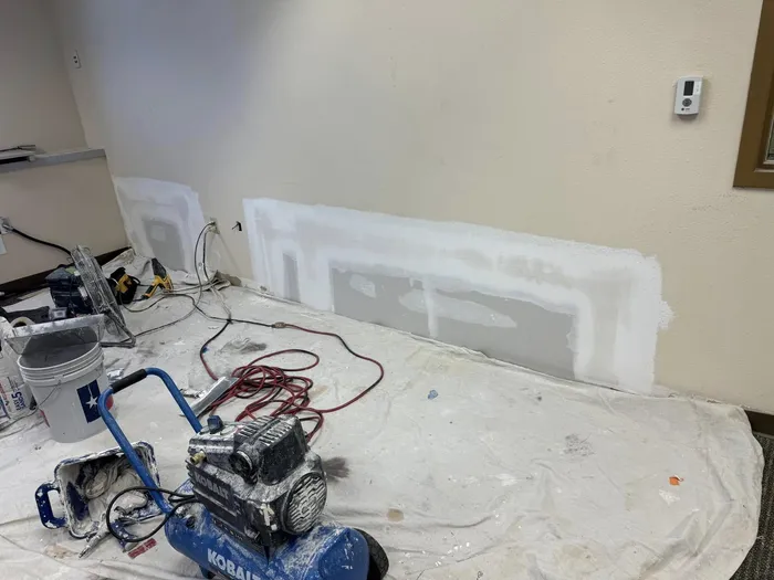Lower wall patches in progress with spray equipment set up