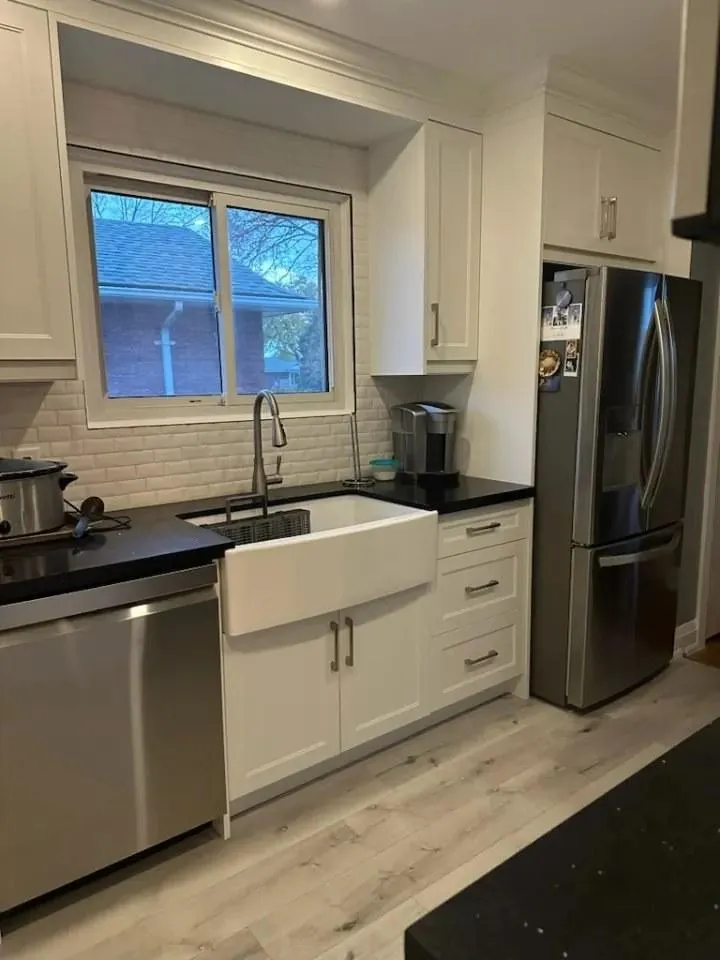 Bright kitchen with white cabinetry, farmhouse sink and dark countertops