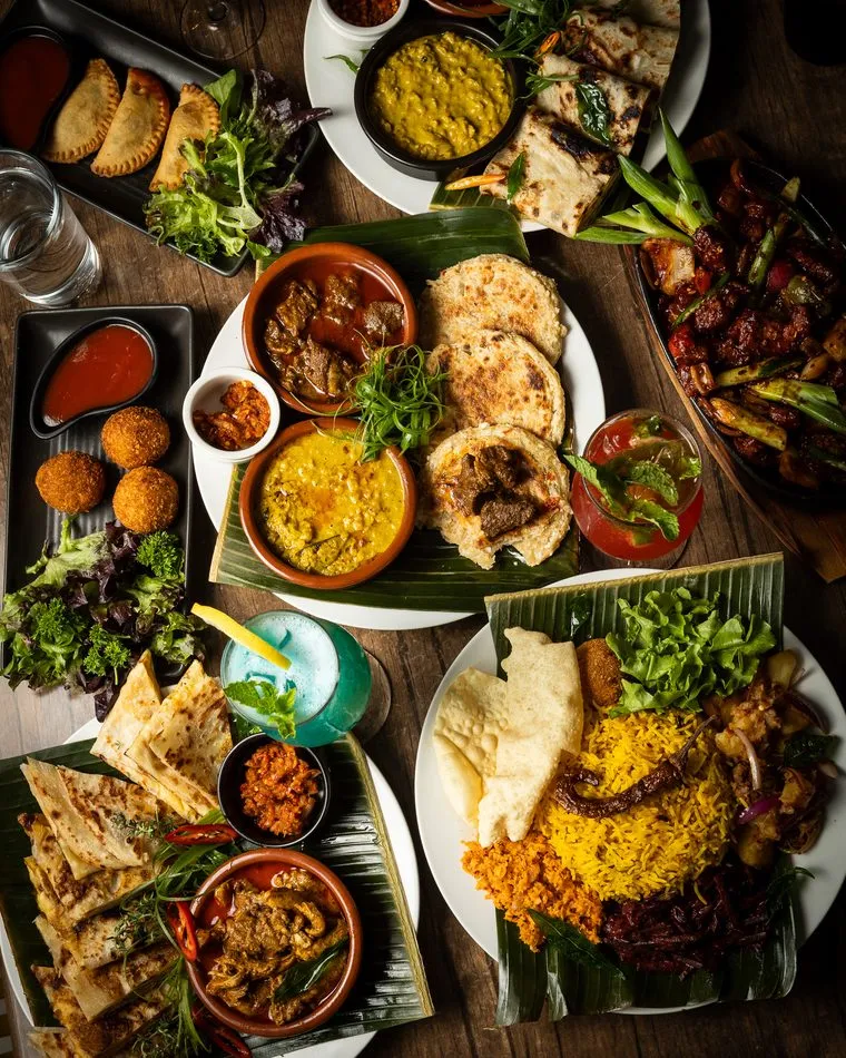 Overhead Sri Lankan feast with coconut roti, curries, dhal, yellow rice and sambols on banana leaf
