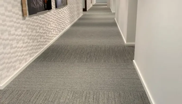 Long apartment hallway with a clean dark grey patterned carpet runner