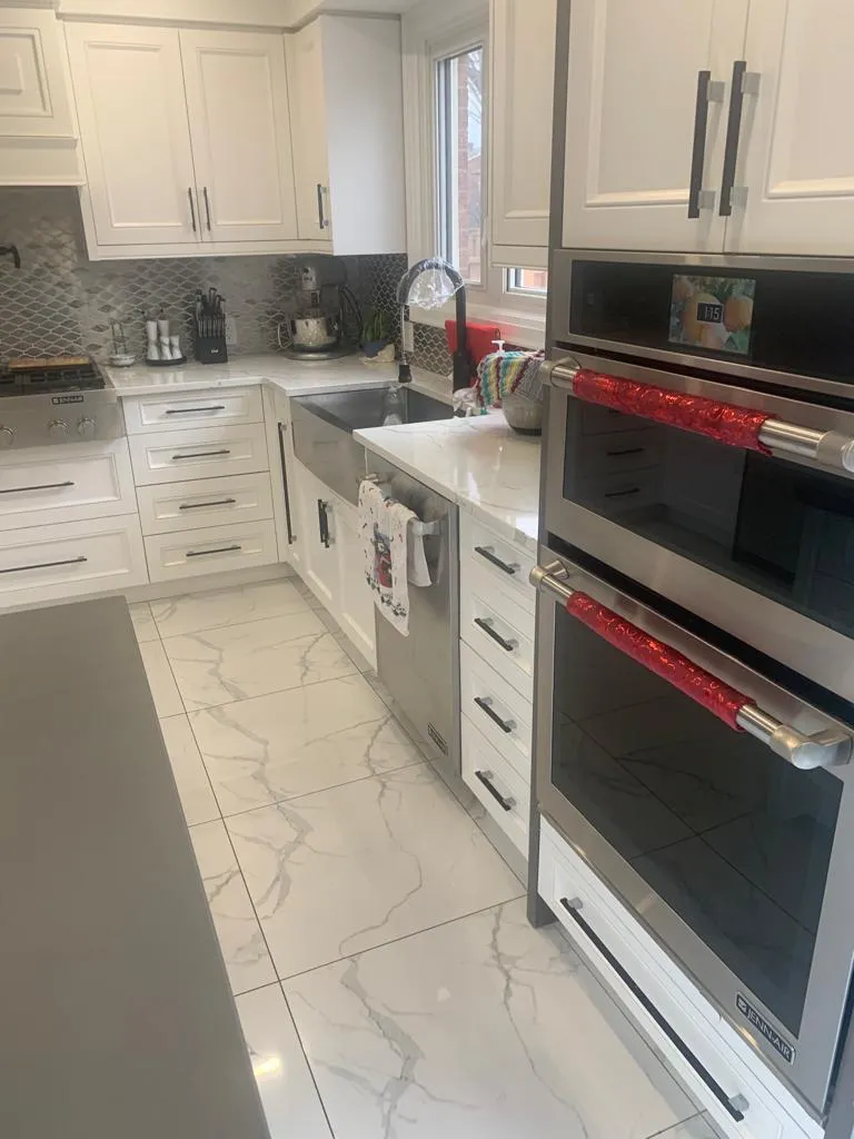 White shaker kitchen with built-in double wall ovens and marble-look floor tile