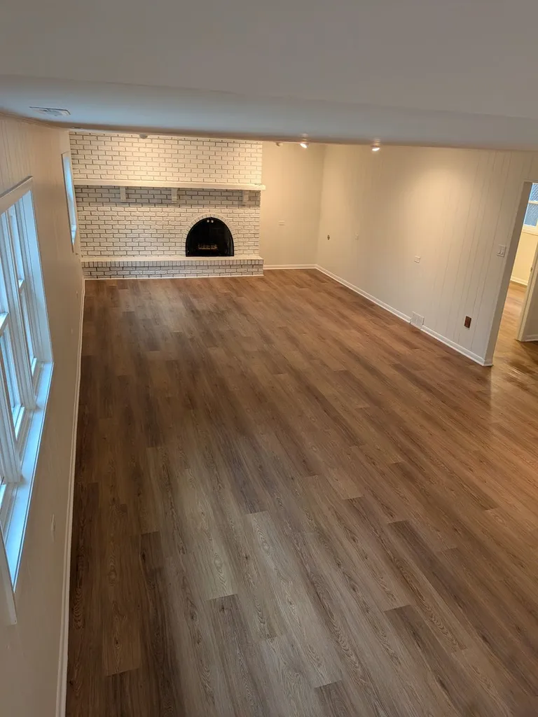 Empty living room with freshly cleaned hardwood floors and fireplace after a whole-home cleaning
