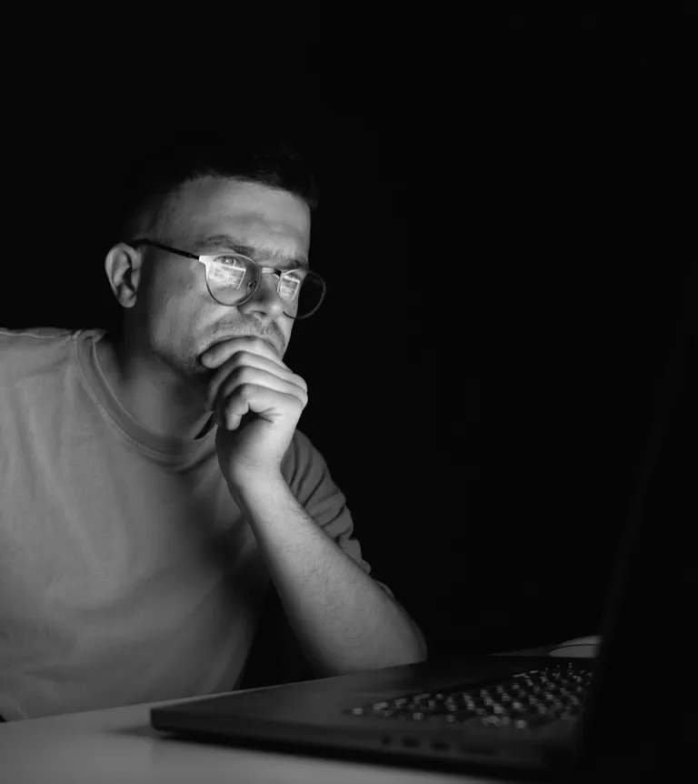 A man at a laptop at night, thinking before he types