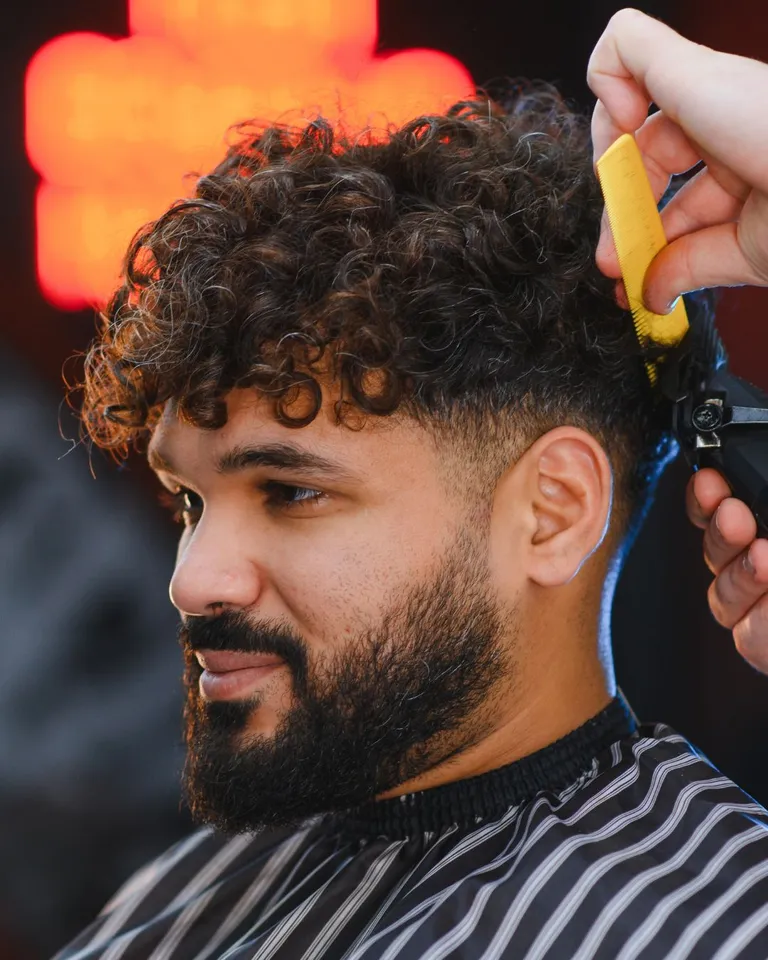Barber cutting curly hair and shaping a full beard at Salon Salman in Pierrefonds