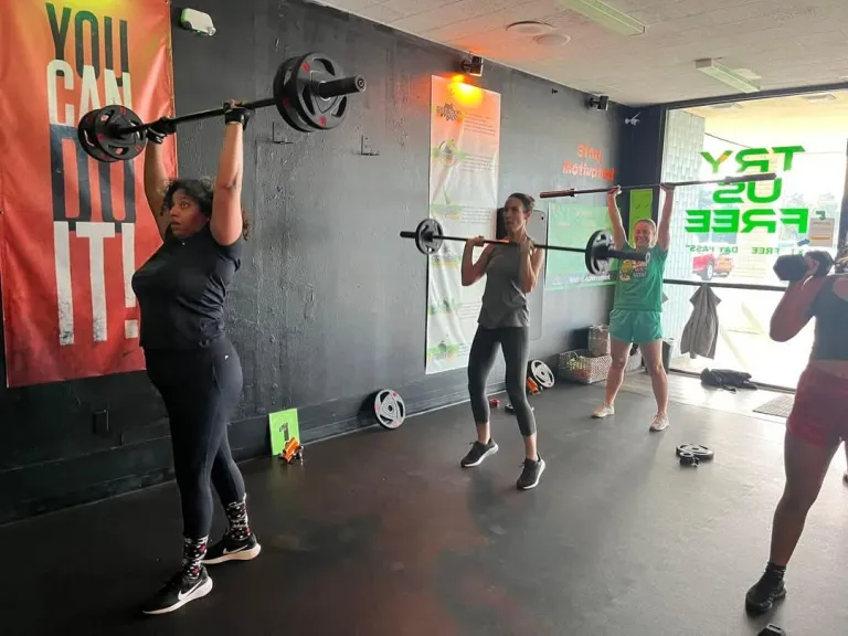 Members pressing barbells overhead at REFUEL Bootcamp Fort Walton Beach