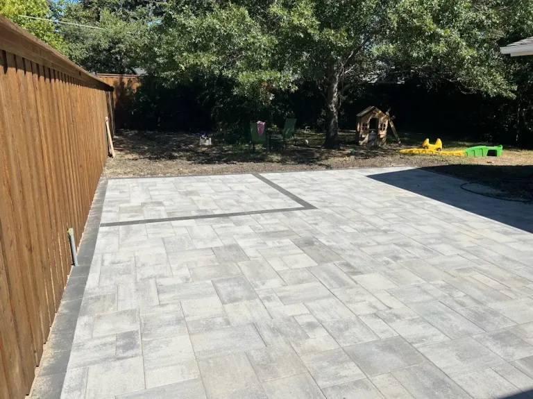 Gray paver patio running along a cedar fence