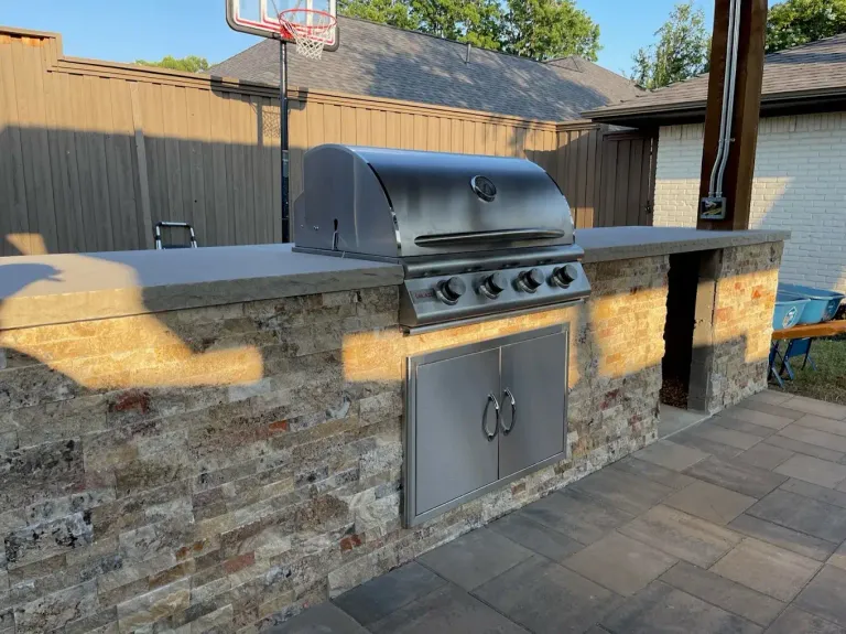 Stone grill island with a stainless grill and storage doors