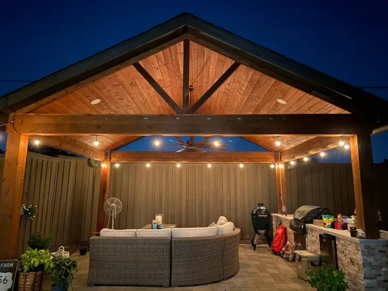 Cedar patio cover with string lights, ceiling fan and outdoor seating at night