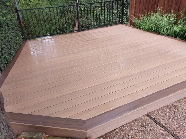 New deck with a raised edge in front of a black metal fence