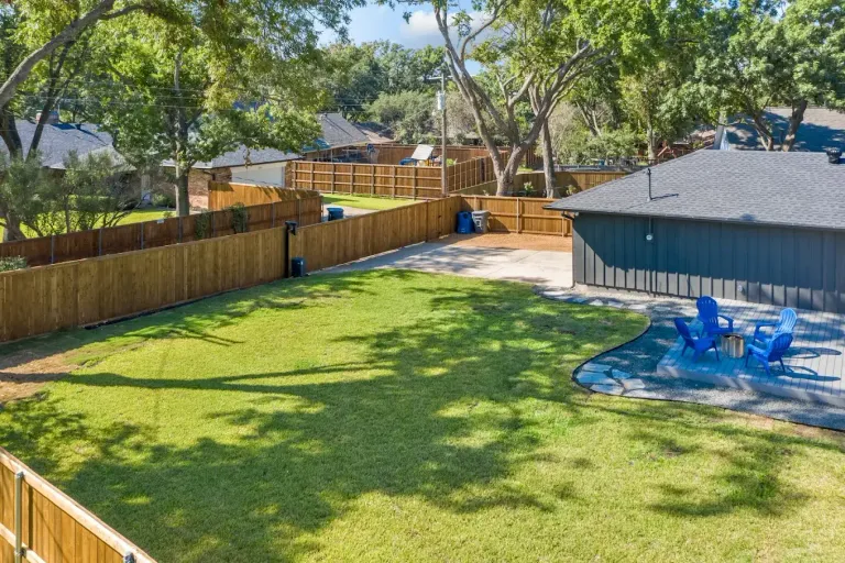 Backyard with a pool, green lawn and a stained wood fence around the property line