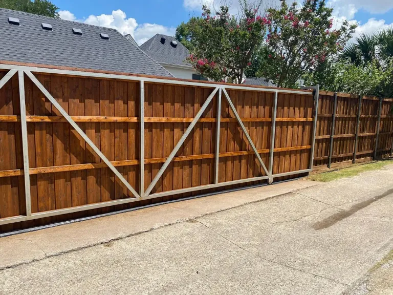 Wide stained wood driveway gate on a steel frame