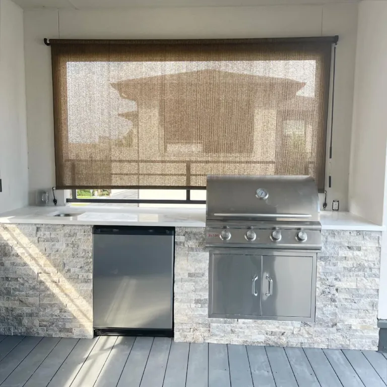 Outdoor kitchen with a built-in stainless grill, fridge and stacked stone base