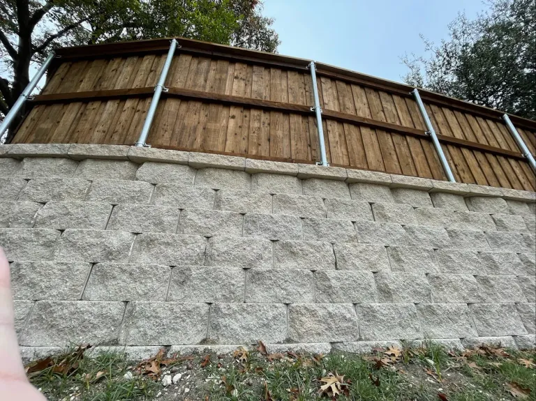 Block retaining wall with a stained wood fence built on top