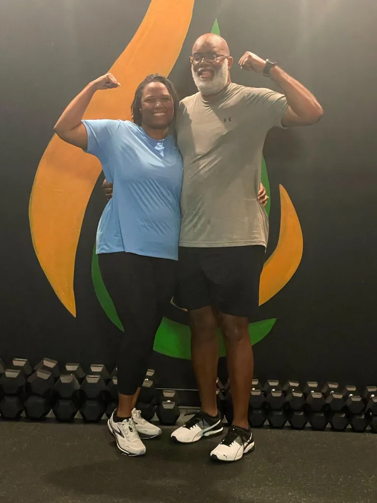 Two members flexing in front of the REFUEL flame mural in Birmingham