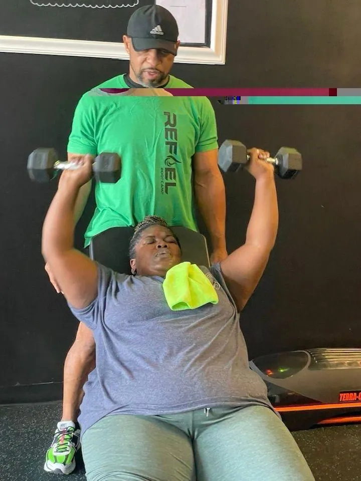Coach spotting a member on dumbbell press at REFUEL Bootcamp Birmingham