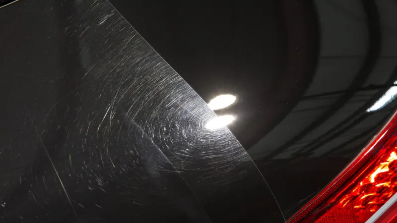 Swirl removal in progress on dark paint under inspection lighting