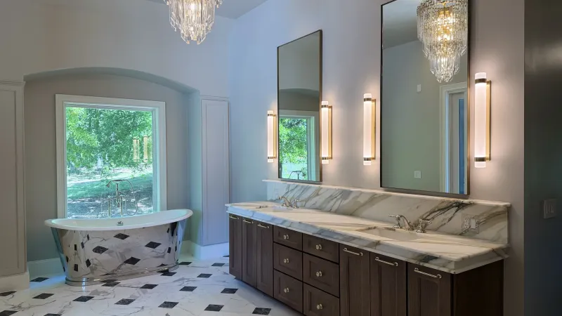 Primary bathroom with a reflective freestanding tub and dark wood double vanity
