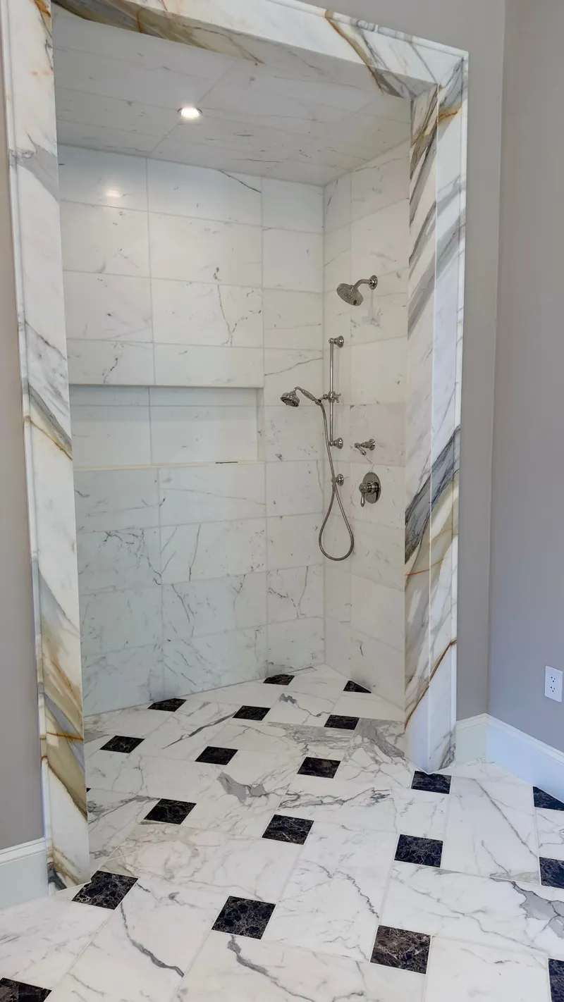 Marble-look shower alcove with a long recessed niche and chrome fixtures