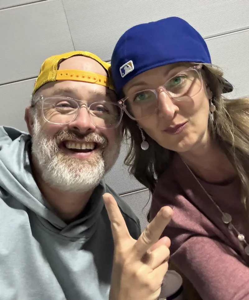 A smiling couple in baseball caps taking a selfie
