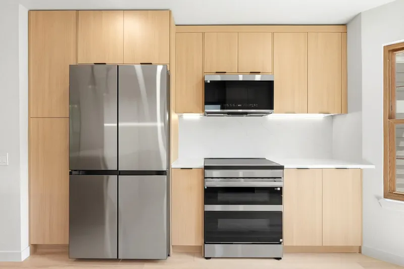 Floor-to-ceiling oak cabinetry with panel-ready refrigerator and slab quartz backsplash