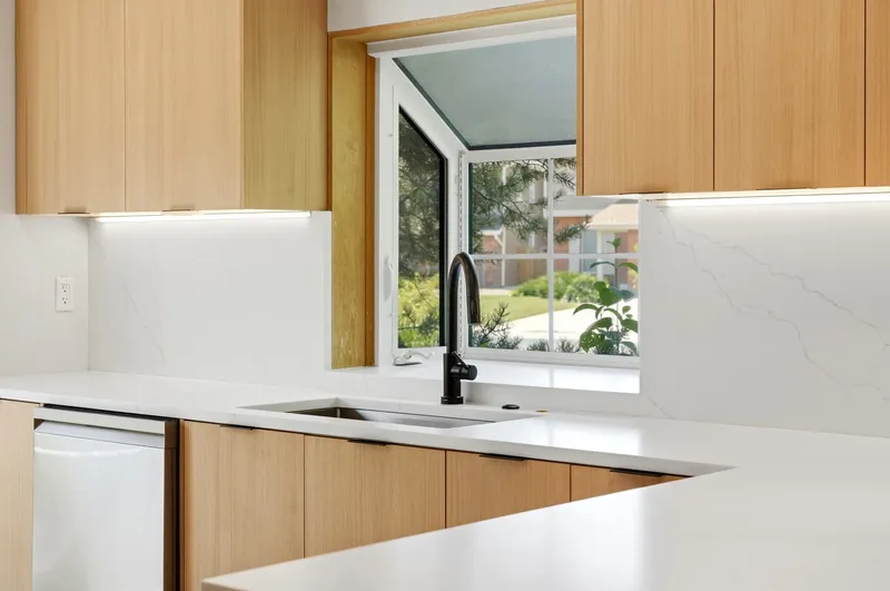 Kitchen garden window over undermount sink with quartz counters and oak cabinetry
