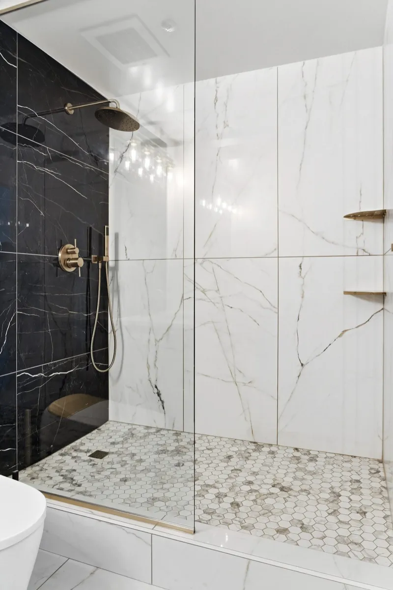 Luxury walk-in shower with brass fixtures and hexagon tile floor
