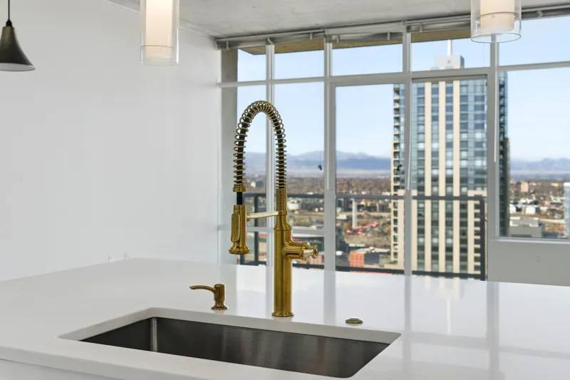 Gold pre-rinse faucet over a quartz island with downtown Denver skyline views