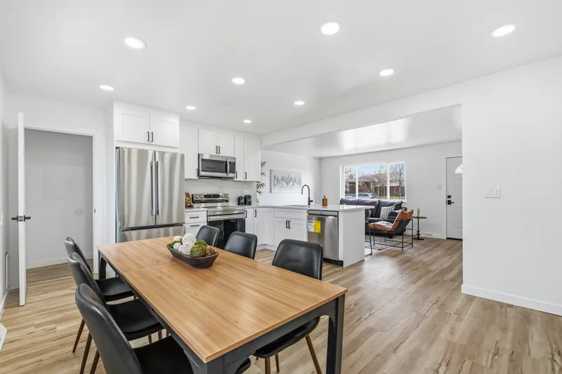 Remodeled open kitchen and dining room with white cabinetry and recessed lighting