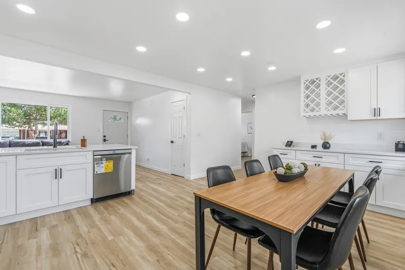 White kitchen with built-in wine rack, dishwasher and quartz counters next to the dining table