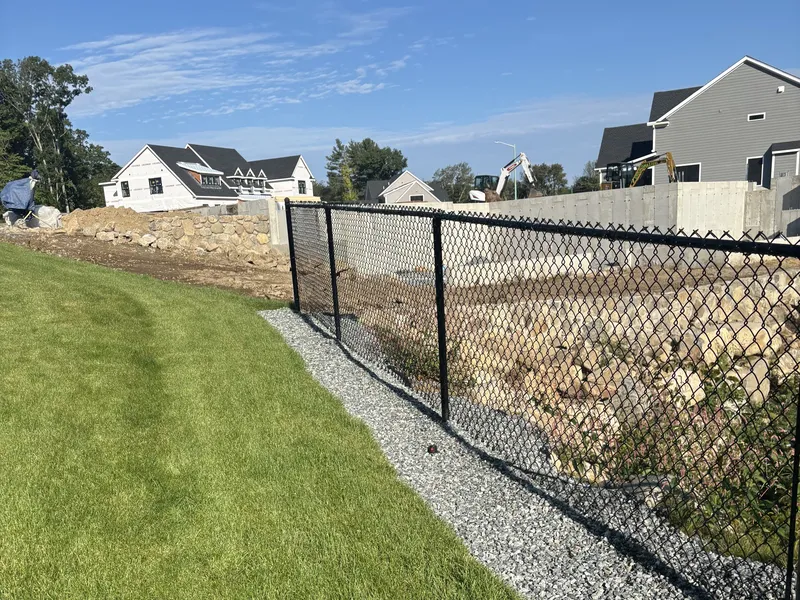 Black chain link fence along a gravel strip at a new development in North Reading by All Fenced In