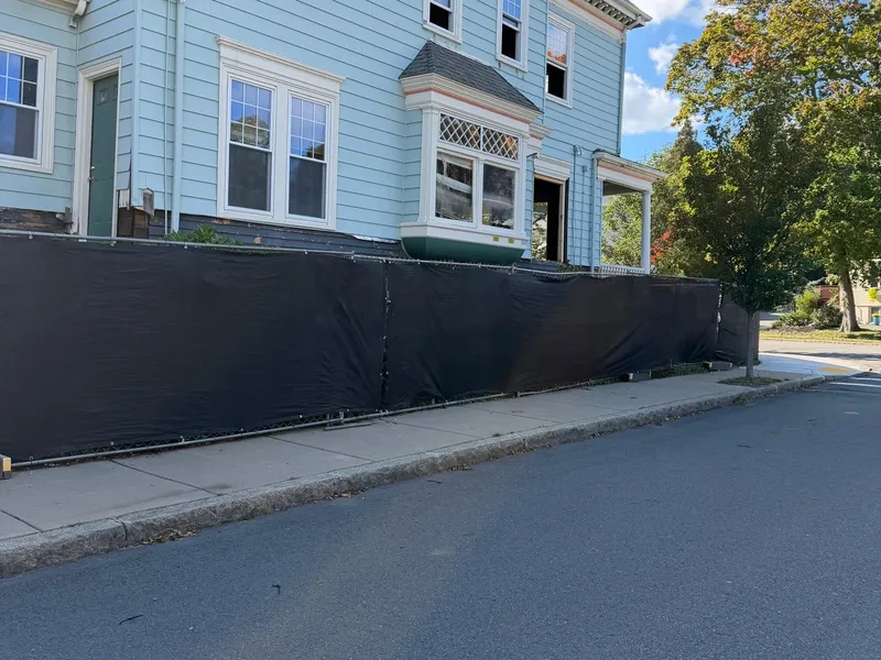 Black chain link fence along a sidewalk by All Fenced In