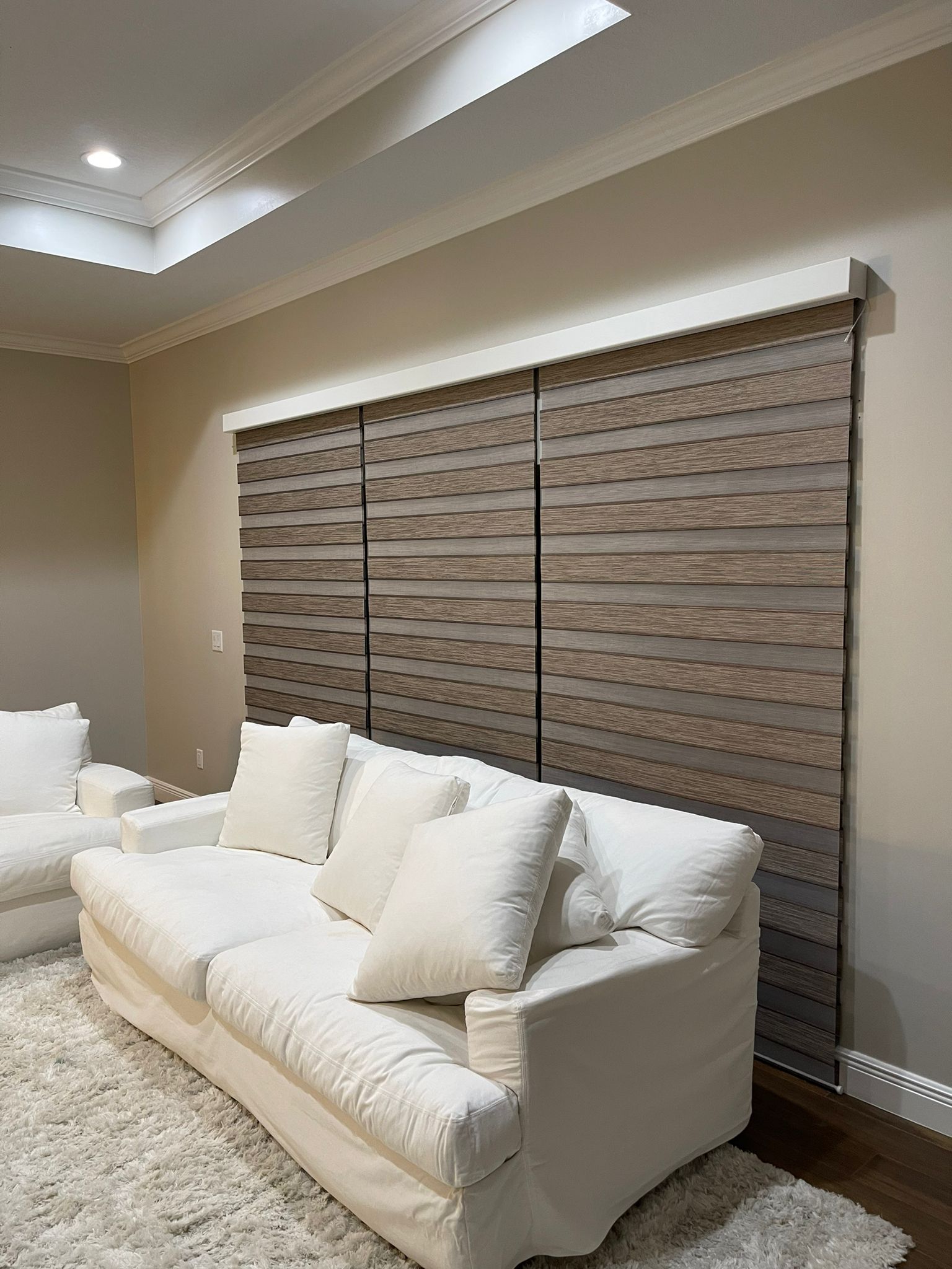 Dark wood-tone zebra shade behind a white sofa