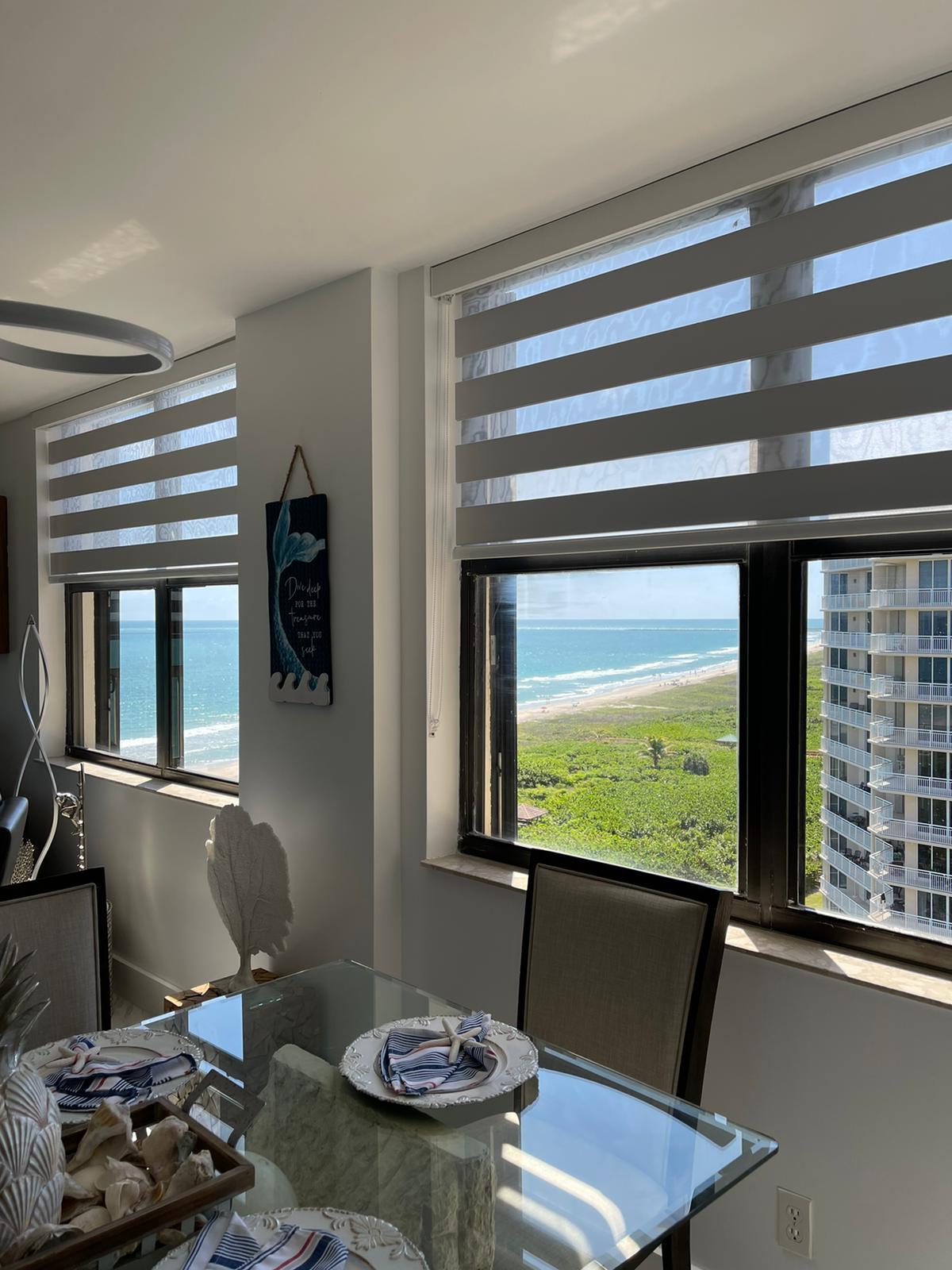 Zebra shades framing an ocean view in a high-floor dining room