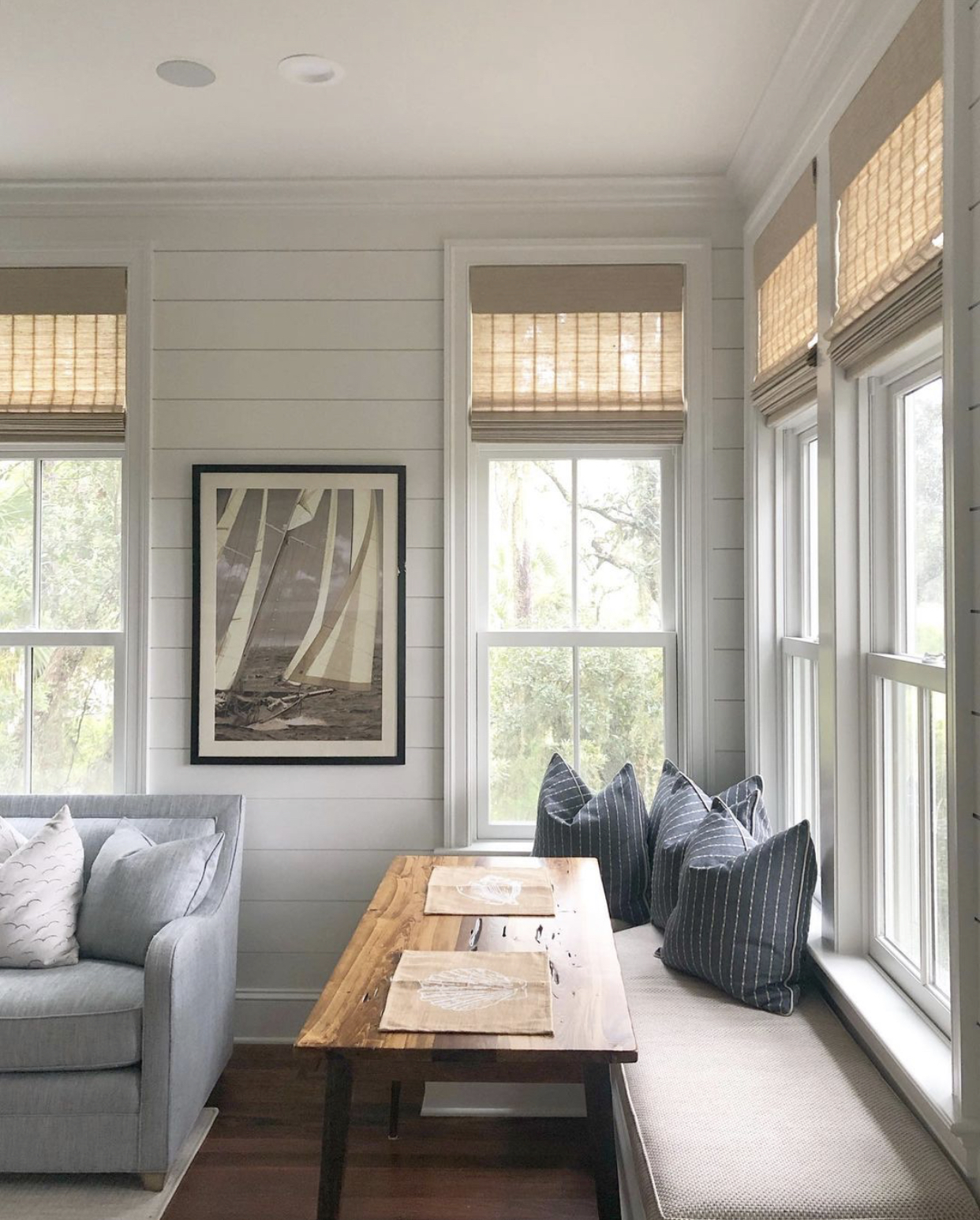 Woven roman shades on the windows of a bright breakfast nook