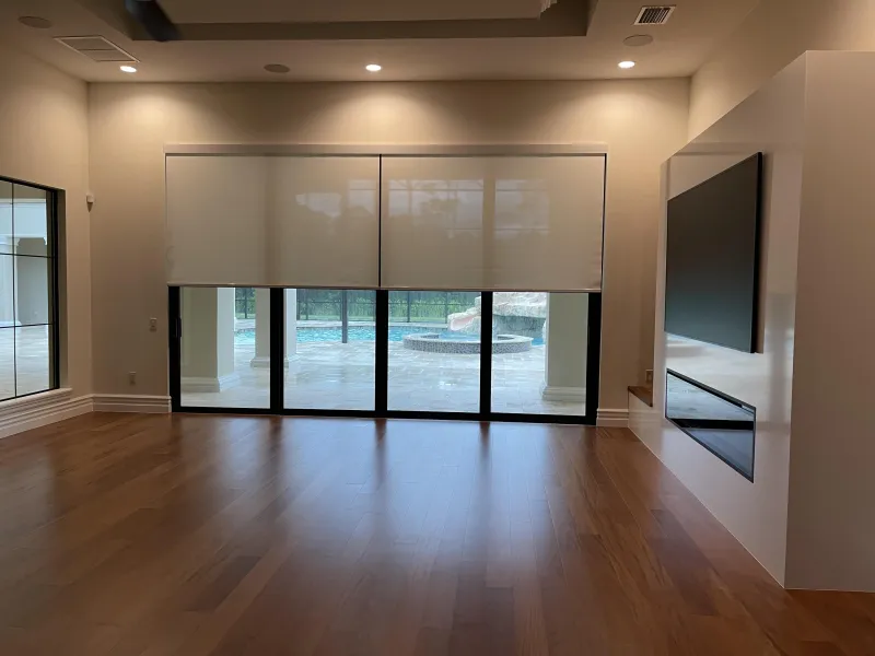Roller shades lowered over sliding doors in a wide living room