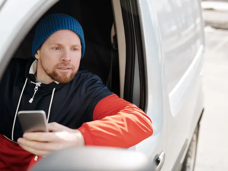 A worker in a van looking at his phone