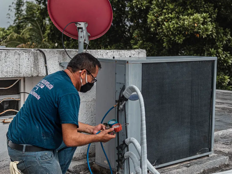 A technician testing an outdoor air conditioning unit