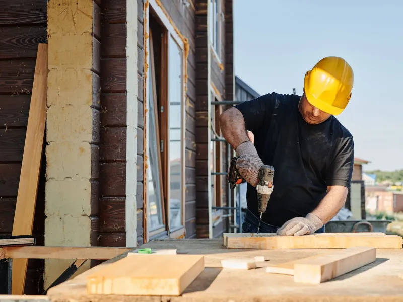 A worker drilling a board on a job site
