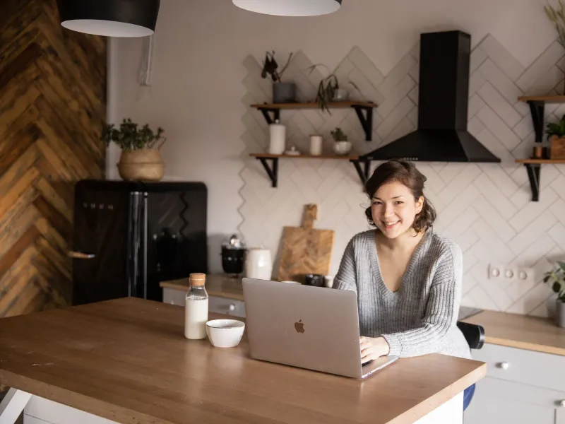 A homeowner at her kitchen counter on a laptop