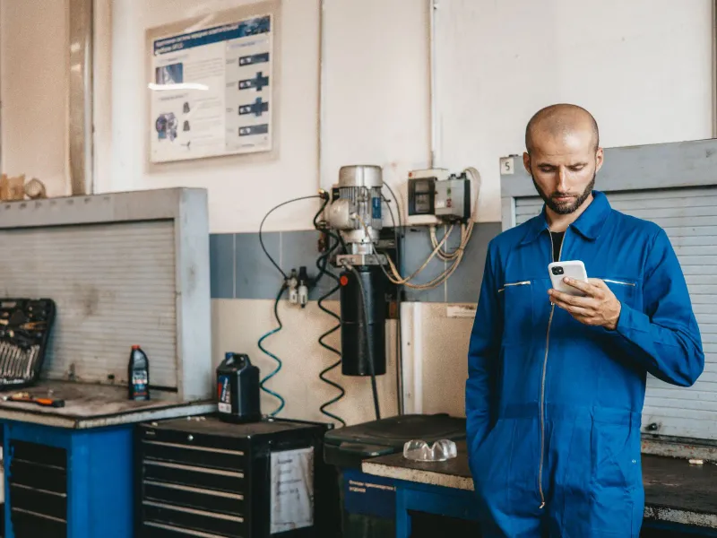 A mechanic in his workshop checking his phone