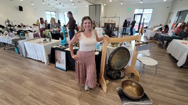 A practitioner beside her gong and sound healing instruments