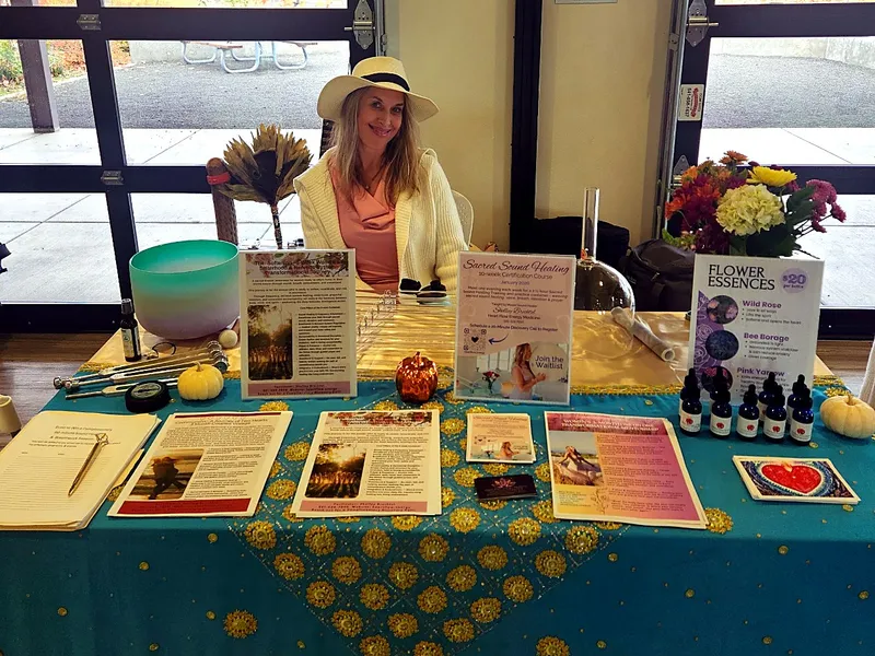 A sound healing vendor at her booth with crystal bowls and flower essences