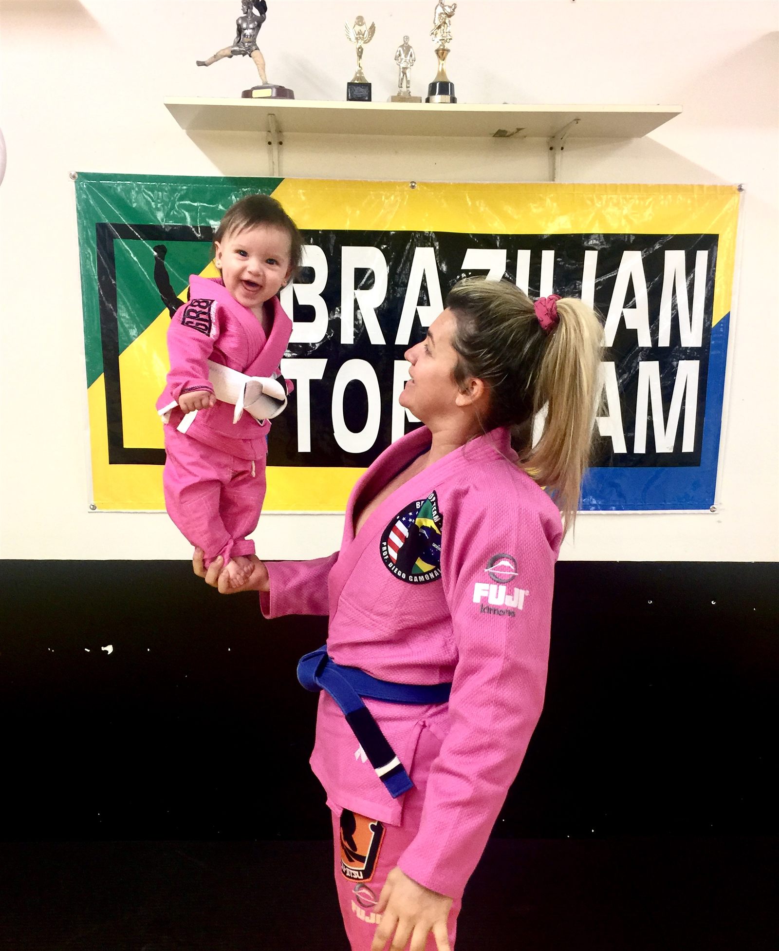 Denise Gamonal in a pink gi holding her baby at Brazilian Top Team