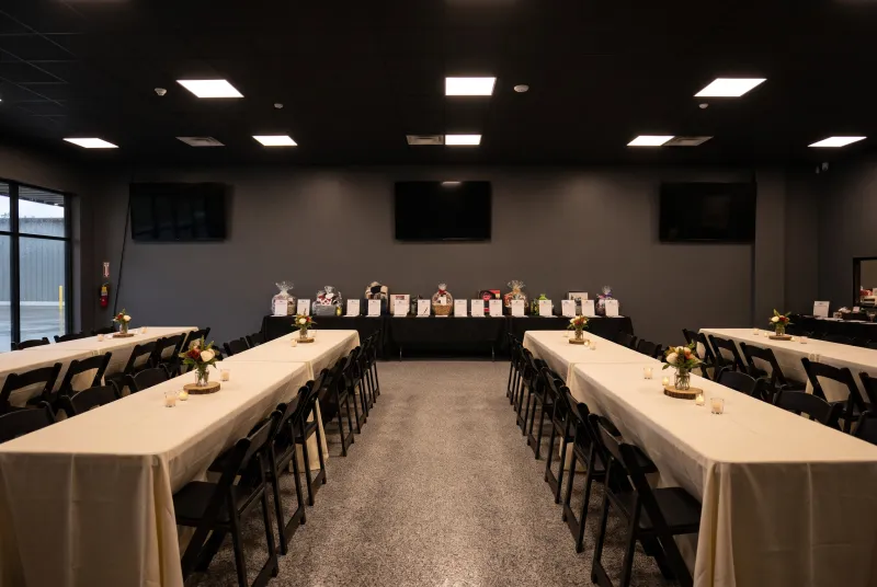 Event room set for a fundraiser dinner with a silent-auction table along the wall
