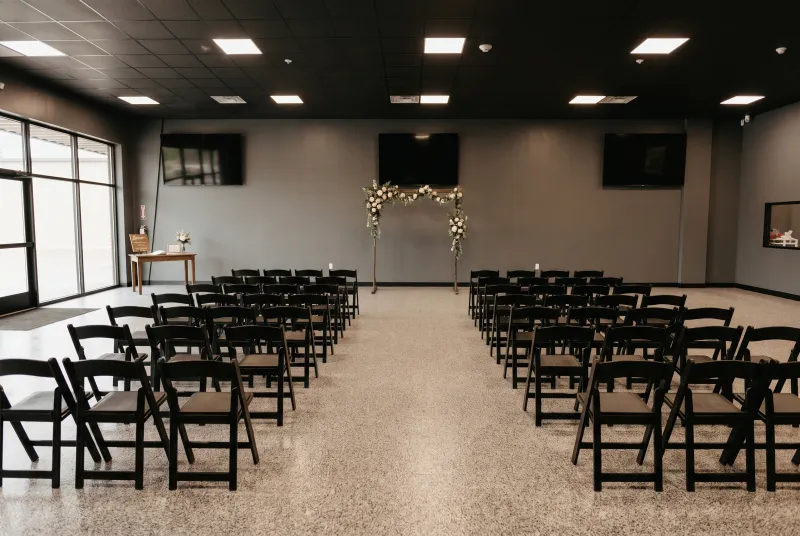 Event room set for a wedding ceremony with chairs facing a floral arch