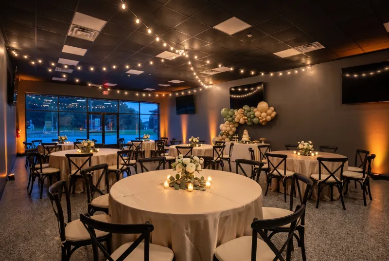 Open event room set for a birthday party with round tables, cream linens and balloons