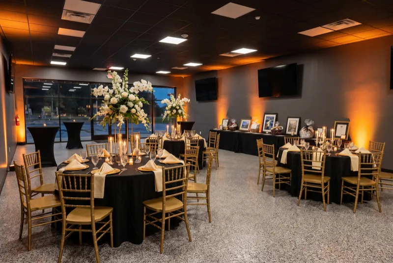 Event room set for a fundraiser dinner with a silent-auction table along the wall