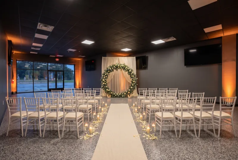 Event room set for a wedding ceremony with chairs facing a floral arch