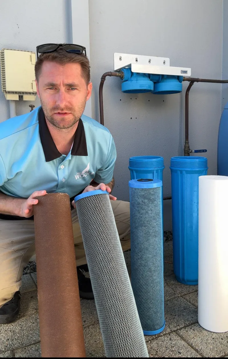 Ashley Woolf with used and new filter cartridges beside an installed system