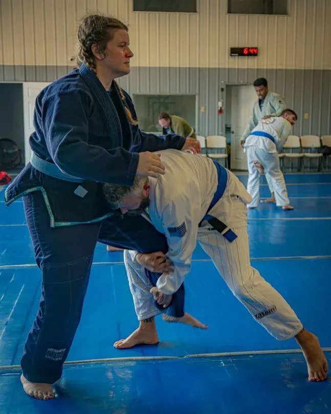 Adult students drilling a single-leg takedown in gis